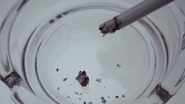 Shake off the ashes from the cigarette in a glass ashtray. Macro. Closeup. Slow mo, slo mo, slow motion, high speed camera, 240fps, 250fps