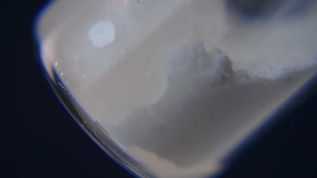 Syringe needle pierces the rubber stopper of the glass vial and diluted from saline the crystals of the medicament. Closeup. Slow motion, slo mo, high speed camera, 240fps, 250fps
