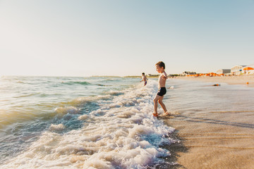 children on the beach go into the ocean. kids play in the waves. copy space for your text