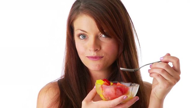Sexy young woman eating fruit from a bowl