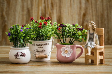 Decorative Artificial Flowers and Angel Trinket on Wooden Background
