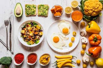 Healthy food for Breakfast. Fried eggs, vegan avocado sandwiches, veggies salad, boiled pumpkin, carrot fresh juice and Different colorful organic vegetables and spices
