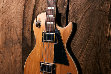 Fototapeta na wymiar Wooden electric bass guitar on wooden background