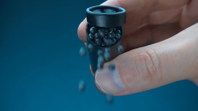Hand pours out lead fraction out of the hunting cartridge on blue background. Macro. Closeup. Slow mo, slo mo, slow motion, high speed camera, 240fps, 250fps