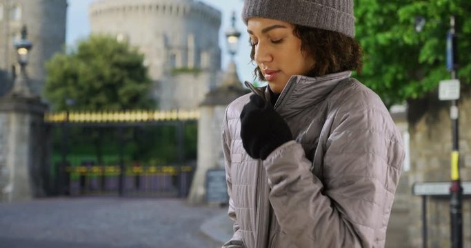 Attractive young black woman zips up her jacket near Windsor Castle