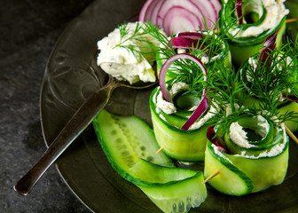 Cucumber rolls with cream cheese, dill and onions decorated on a plate
