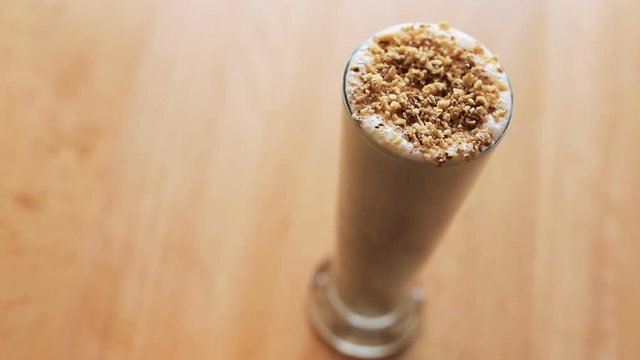 View of glass of latte with nuts on background