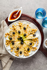 The leaves of Belgian endive with hummus, chickpeas and black olives. With strong olive oil of red pepperoncino. Modern delicious food for vegetarians and gourmets.