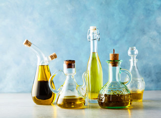 different shapes, types and sizes of cruets with olive oil on the table on blue
