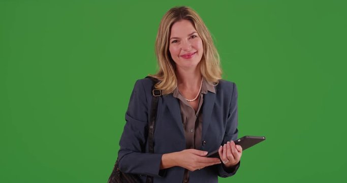 Middle aged adult Caucasian business woman using tablet device on green screen. On green screen to be keyed or composited.