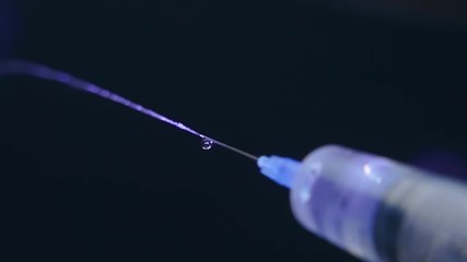 From the needle of the plastic syringe a jet of water, saline solution, medicinal solution on black background. Macro. Closeup. Slow motion, high speed camera, 240fps, 250fps
 - Powered by Adobe
