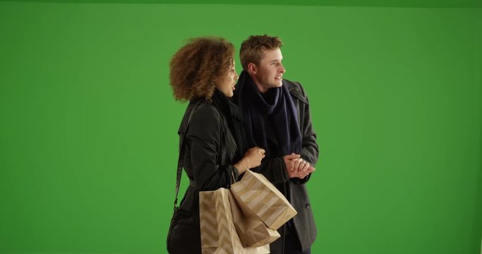Attractive couple waiting for ride outdoors with shopping bags on green screen. On green screen to be keyed or composited. 