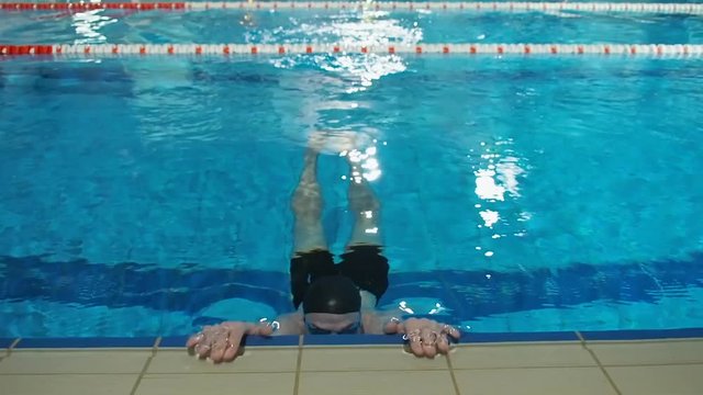 Swimmer swims in the pool. The athlete emerges from the pool.