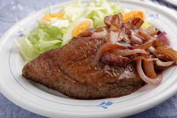 Beef steak with onion and salad