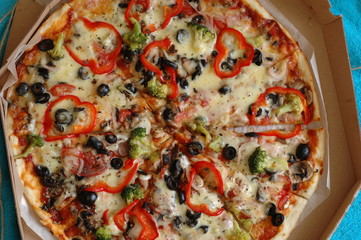 A large pizza in a cardboard box is a top view.