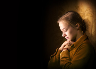 Young woman praying - obrazy, fototapety, plakaty