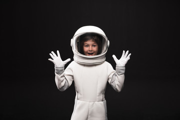 Wow. Waist up portrait of wondered little astronaut in helmet and protective suit is standing while...