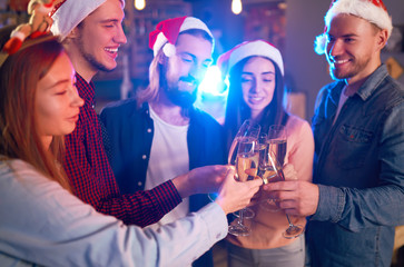 Group of friends having fun. young people laugh. celebrating New Year together. Group of beautiful young people in Santa hats. Blur Background.
