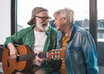 Waist up portrait of retired man and woman expressing gladness enjoyment and love. Wife is looking...