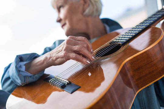 Close up of mature woman performing song while looking aside. Focus on musical instrument