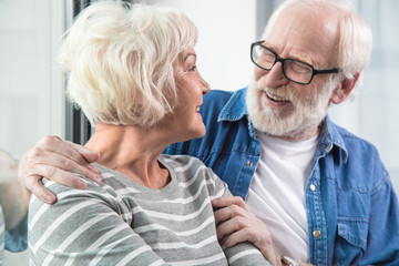 Waist up portrait of married senior couple enjoying rest together while sitting near window