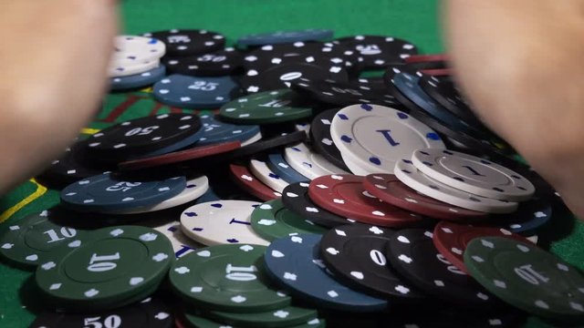 Poker player increasing his stakes throwing tokens onto the gaming table.