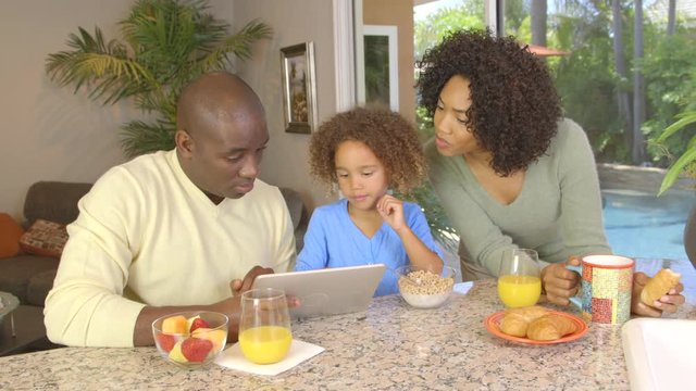 African American family  eating breakfast and using laptop