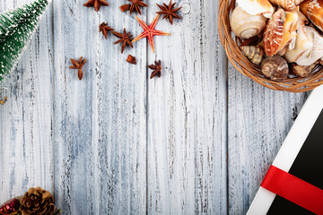 Presents wrapped with red ribbon, new year's attributes and basket with sea shells on vintage wooden background