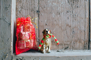 statue of the dog and a bag with Christmas gifts on vintage wooden background