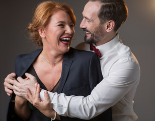 Portrait of happy man is wearing his jacket on female shoulders. Woman is enjoying hug and smiling. Isolated