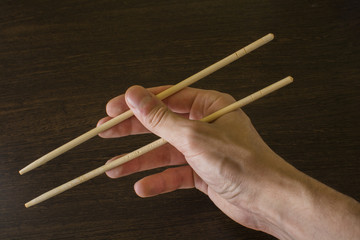 chopsticks in the right hand on the background of wood