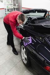 Fototapeta na wymiar A man cleaning car with microfiber cloth, car detailing (or valeting) concept. Selective focus. 