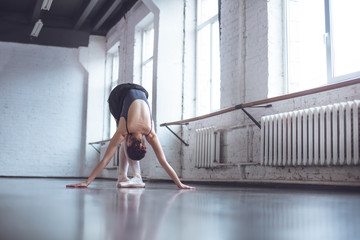 Fototapeta na wymiar Young ballet dancer bend down in studio active lifestyle