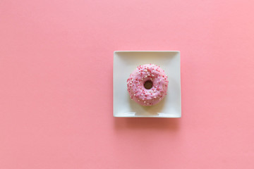 Pink doughnut on pink background with space for copy