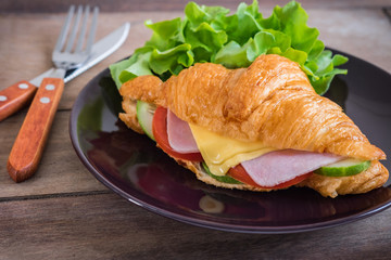Croissant with ham, cheese and vegetable on plate