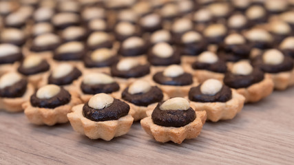 Coconut cupcakes with chocolate filling and almond garnish. Decorative sweet Christmas pastry stacked on a wood background. Small depth of sharpness.