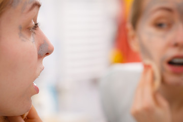 Woman removing mud facial mask with sponge