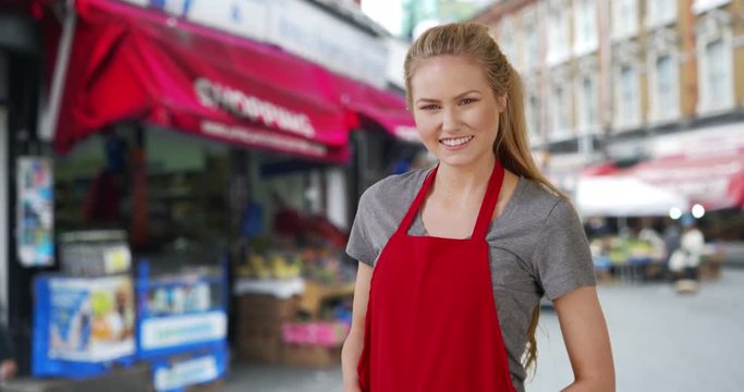 White female grocery store employee poses outside in street