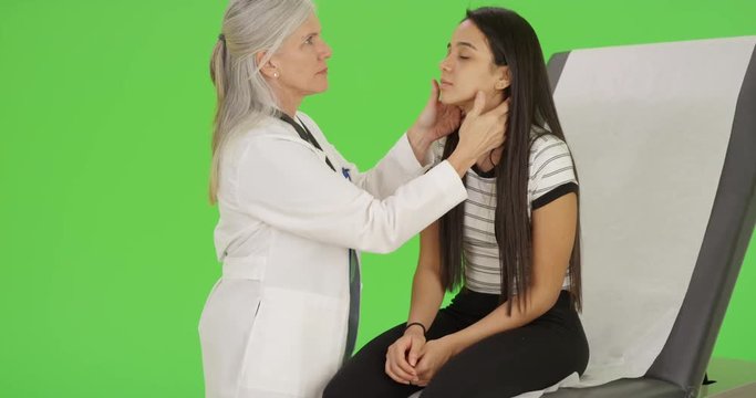 An older doctor gives a girl an annual check up on green screen. On green screen to be keyed or composited. 