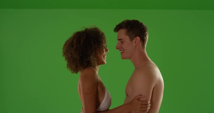 Portrait of young interracial couple on evening shoreline on green screen. On green screen to be keyed or composited. 