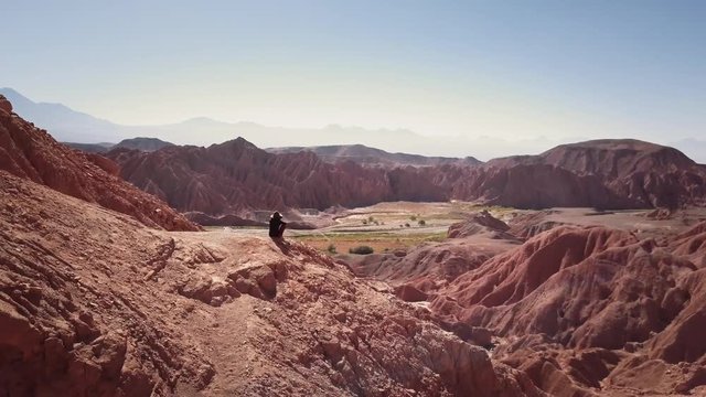 Aerial shot of female trekker standing at the cliff contemplating the horizon of the Atacama desert. 4k