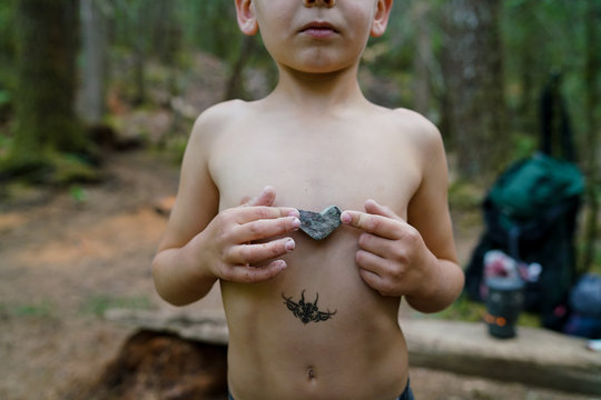 Mid section of a boy holding a heart shaped rock