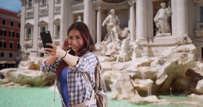 Happy attractive Japanese woman taking selfies at Trevi Fountain