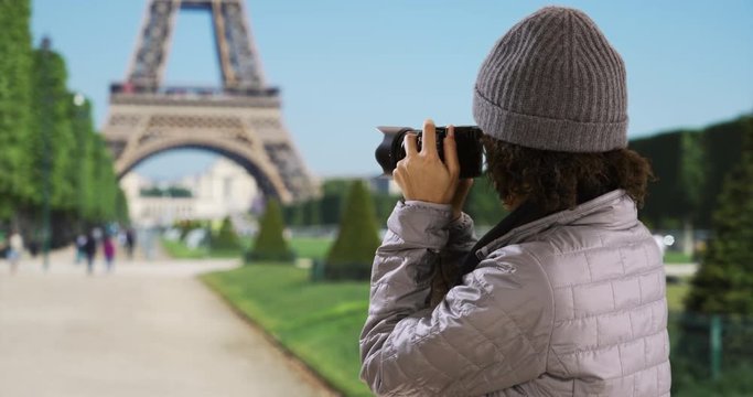 Cute millennial black female traveling in Europe takes picture of Eiffel Tower