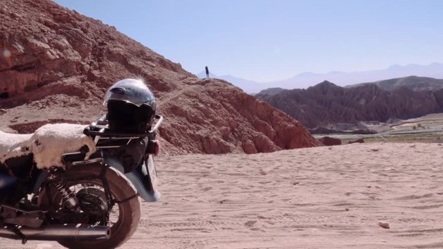 Man contemplating the horizon of the Atacama desert, motorcycle parked on the dirt road. 4k