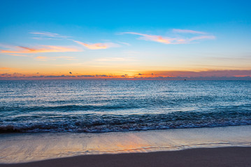 Obraz premium bright colorful sky reflection off the ocean on a calm morning at the beach