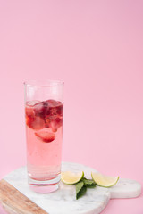 A glass of pink water with frozen strawberry and lingonberry with liced citrus