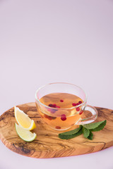 A cup of hot tea with lingonberry, mint and sliced citrus