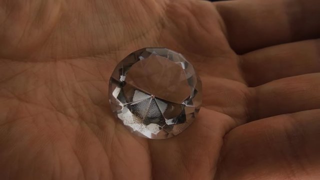 The hand releases a huge diamond and it falls and rotates and shiny all sideson black background. Closeup. Slow mo, slo mo, slow motion, high speed camera, 240fps, 250fps
