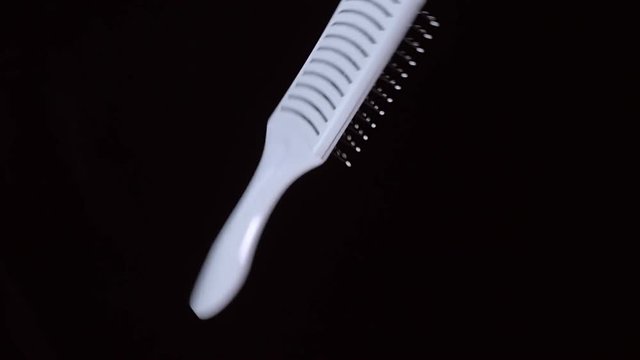 White comb flies and rotates on a black background. Close Up. Slow mo, slo mo, slow motion, high speed camera, 240 fps, 250 fps